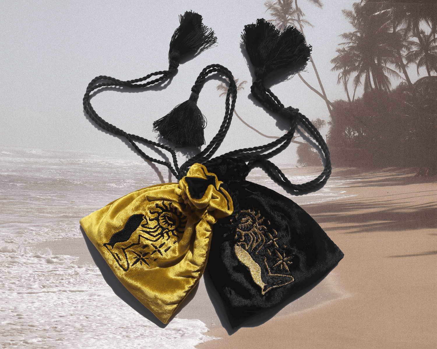 2 velvet pouches, black and yellow, laying on a picture of a tropical sunny beach with sand, the palms and the ocean.