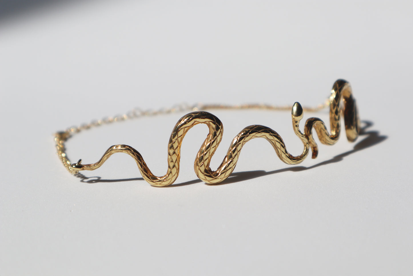 The Kunda Chocker resembles a snake unfolding on your neck, as a symbol of the Kundalini Awakening, reaching the Throat Chakra. Elegant and modern gold wavy snake chocker.